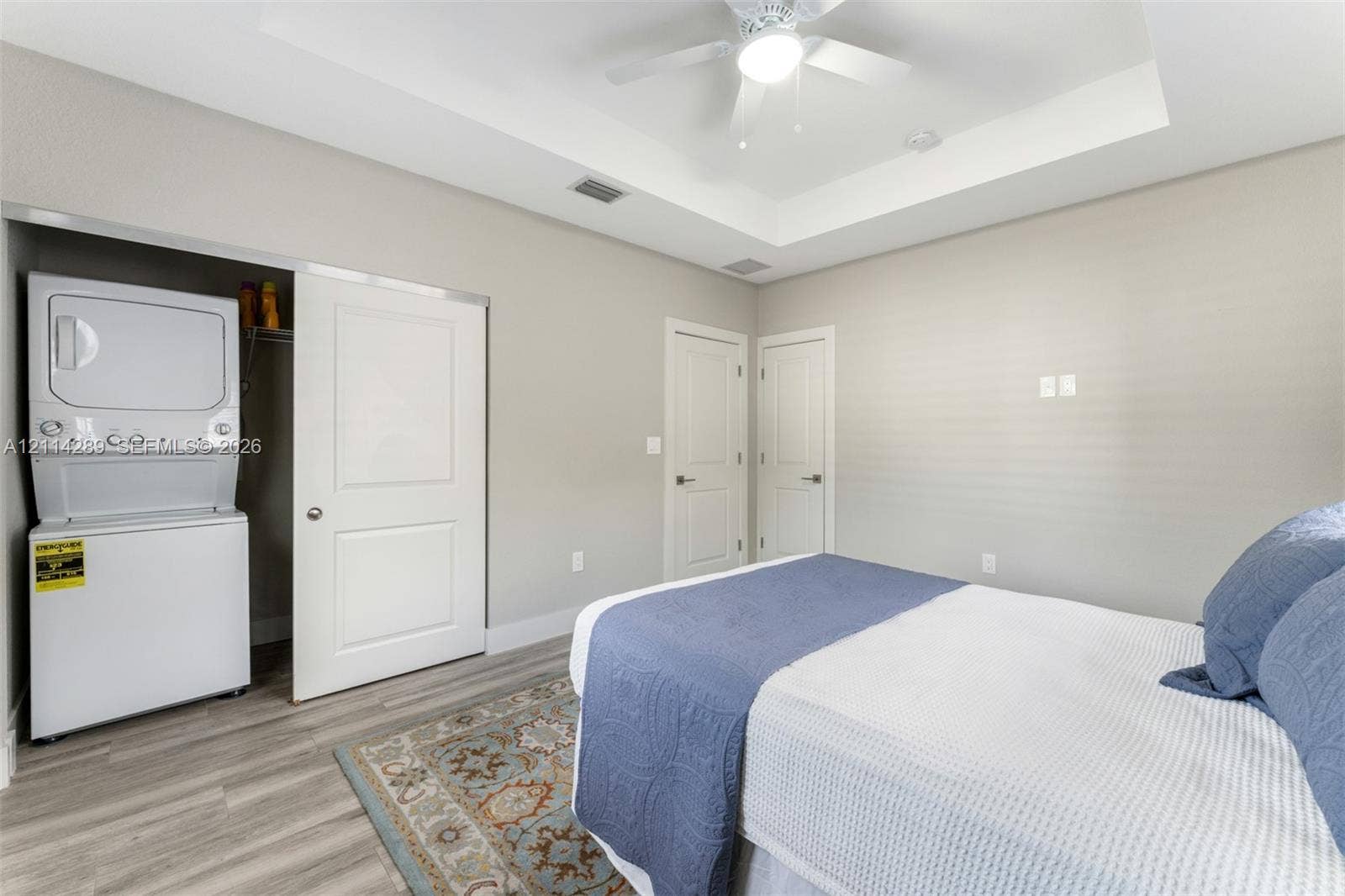 646 Cabrera Street, Key Largo, FL 33037 Tray ceiling featuring a central light-integrated ceiling fan, wood-finish flooring, and built-in stacked laundry unit
