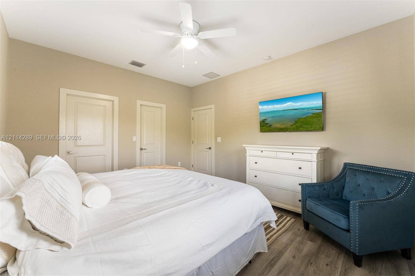 646 Cabrera Street, Key Largo, FL 33037 Room featuring wood-finish flooring, a white ceiling fan with integrated lighting, and three interior doors with neutral hardware