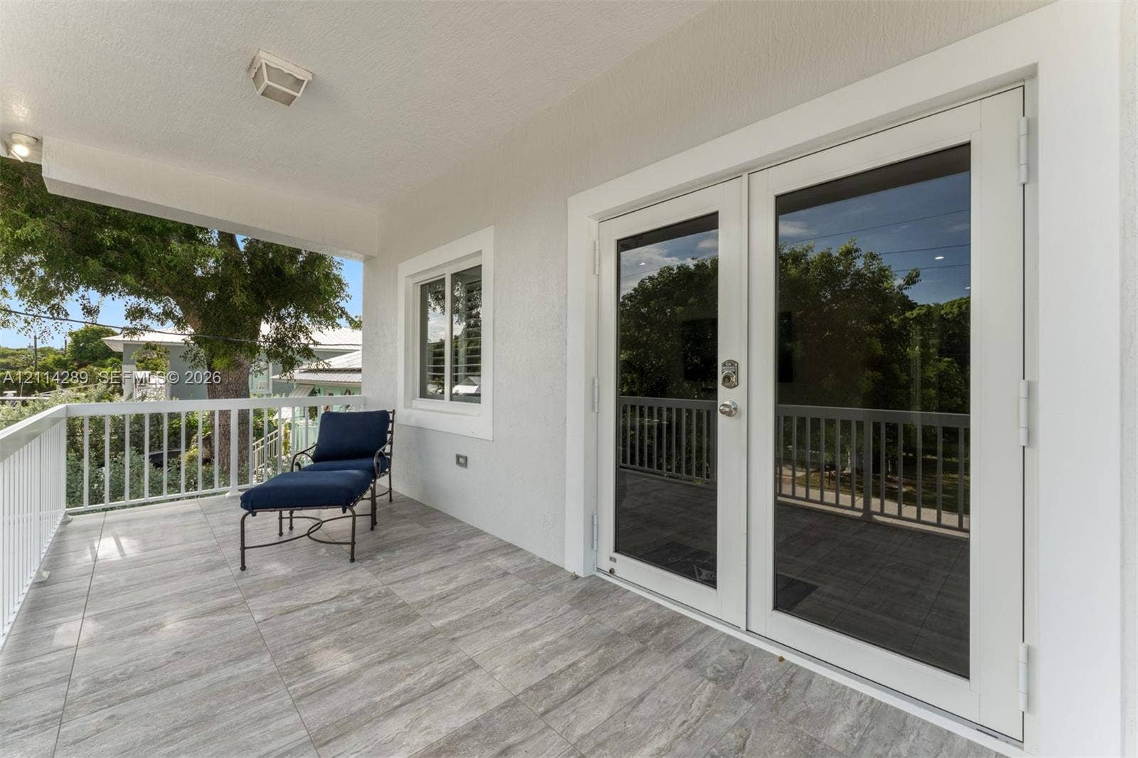 646 Cabrera Street, Key Largo, FL 33037 Covered balcony featuring wood-finish tile flooring, white metal railing, and glass-paned double doors