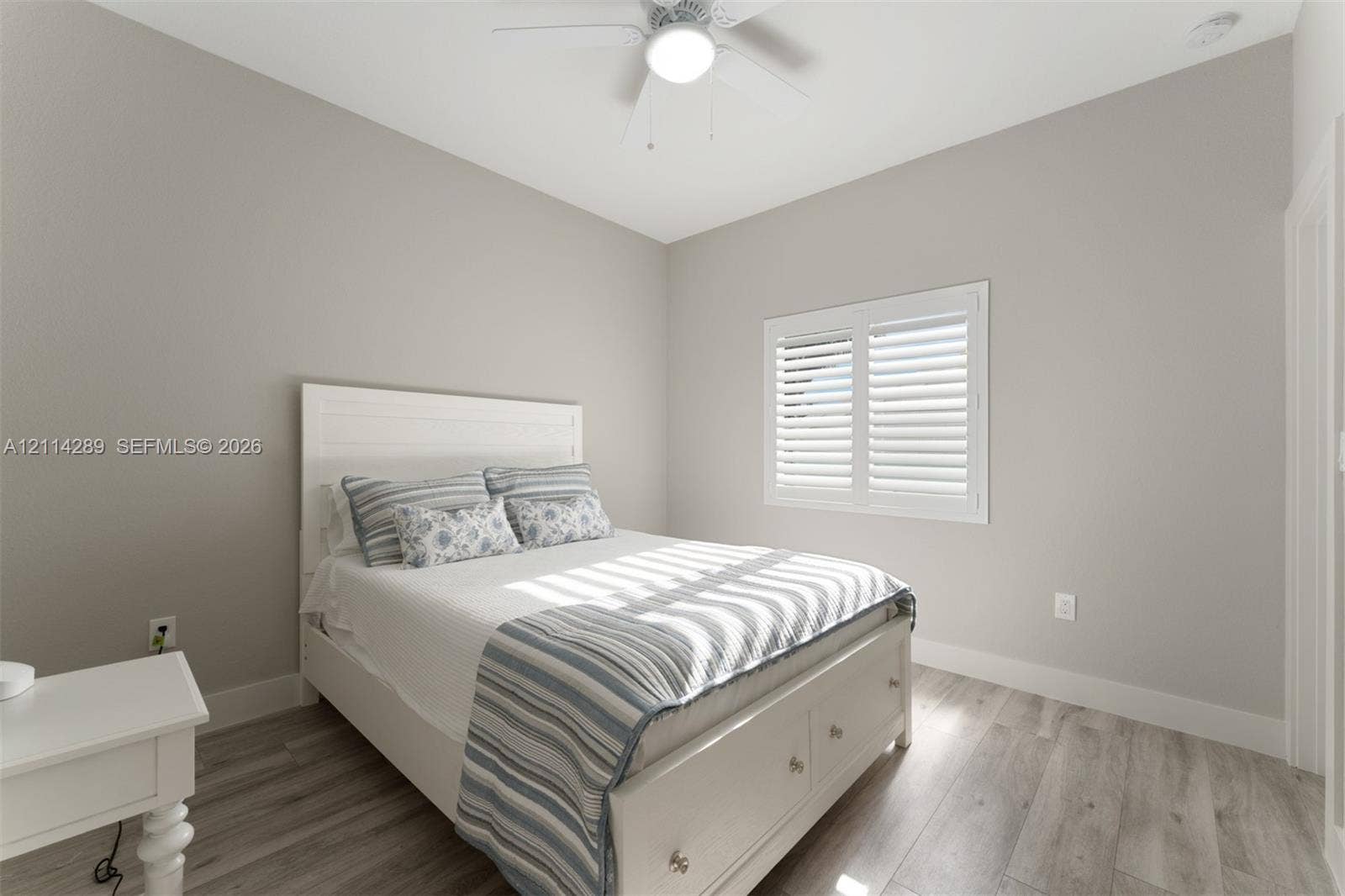 646 Cabrera Street, Key Largo, FL 33037 Neutral-toned interior featuring wood-finish flooring, white plantation shutters, and a ceiling fan with integrated lighting