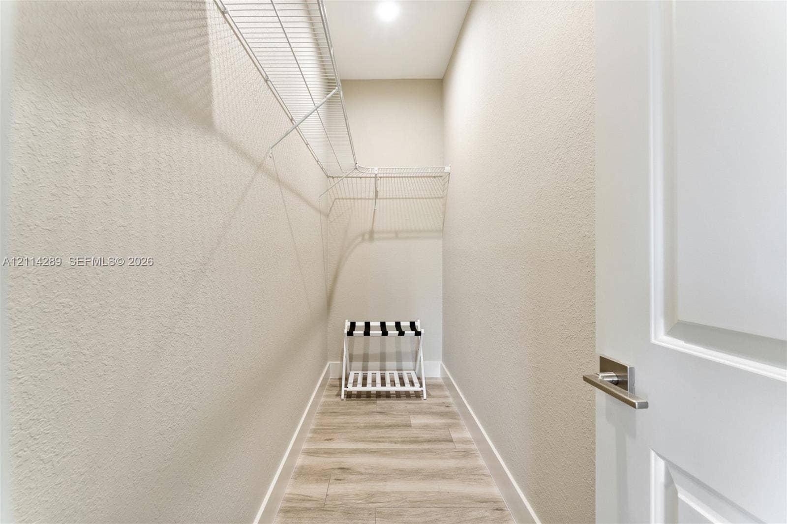 646 Cabrera Street, Key Largo, FL 33037 Walk-in closet featuring wood-finish flooring, white paneled door with brushed nickel hardware, and multi-level wire shelving