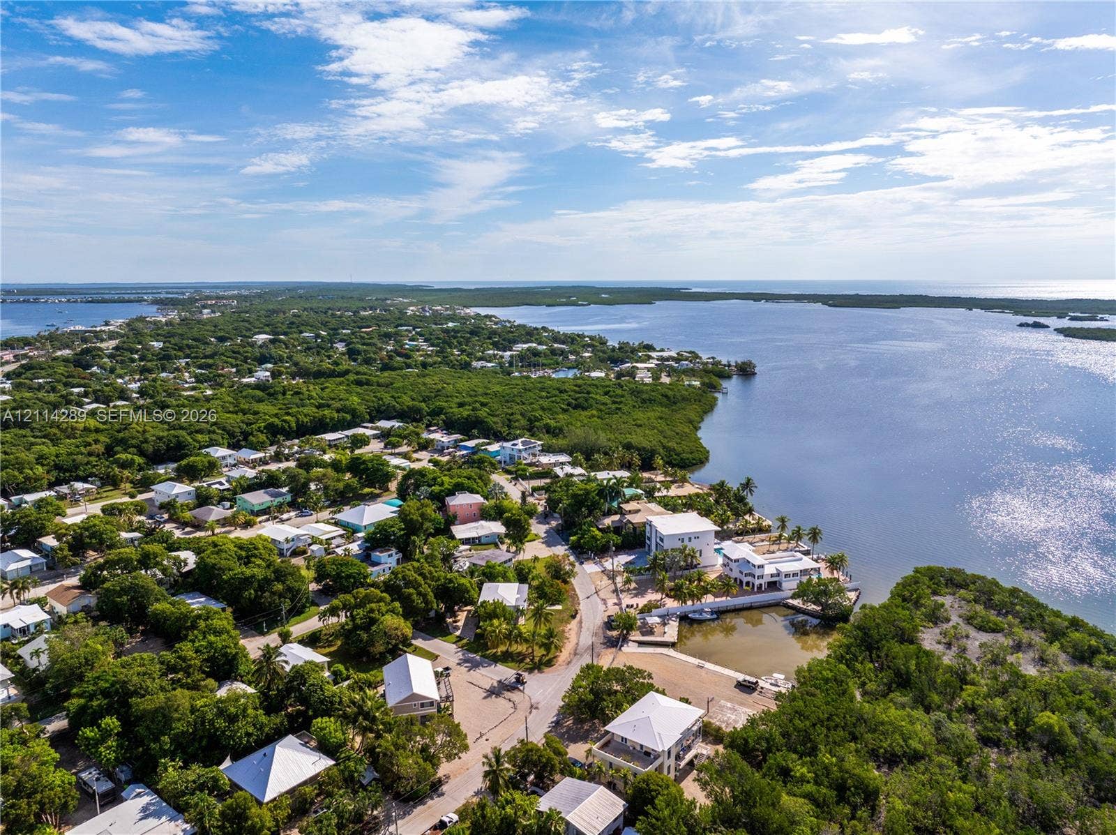 646 Cabrera Street, Key Largo, FL 33037 Aerial perspective of a coastal residential area featuring waterfront property, a private boat slip, dense tree canopy, and access to open water