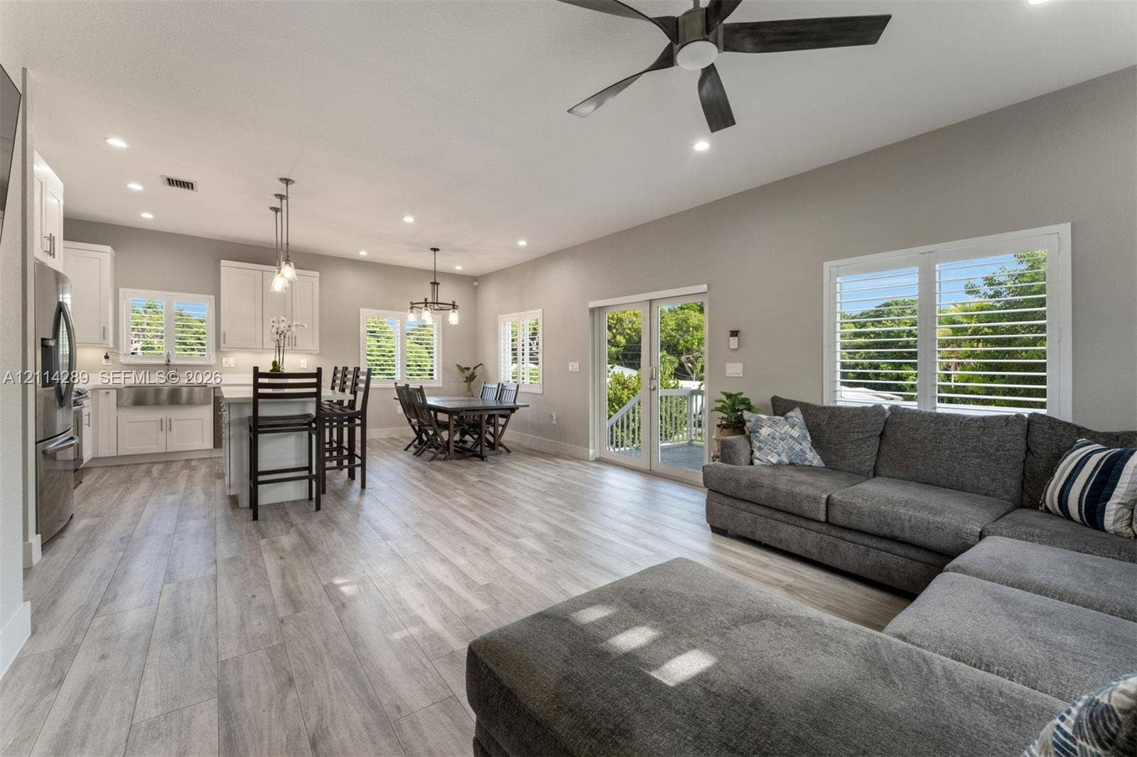 646 Cabrera Street, Key Largo, FL 33037 Open-concept living space featuring wood-finish flooring, recessed lighting, white shaker-style cabinetry, stainless steel apron-front sink, and dual glass paneled doors