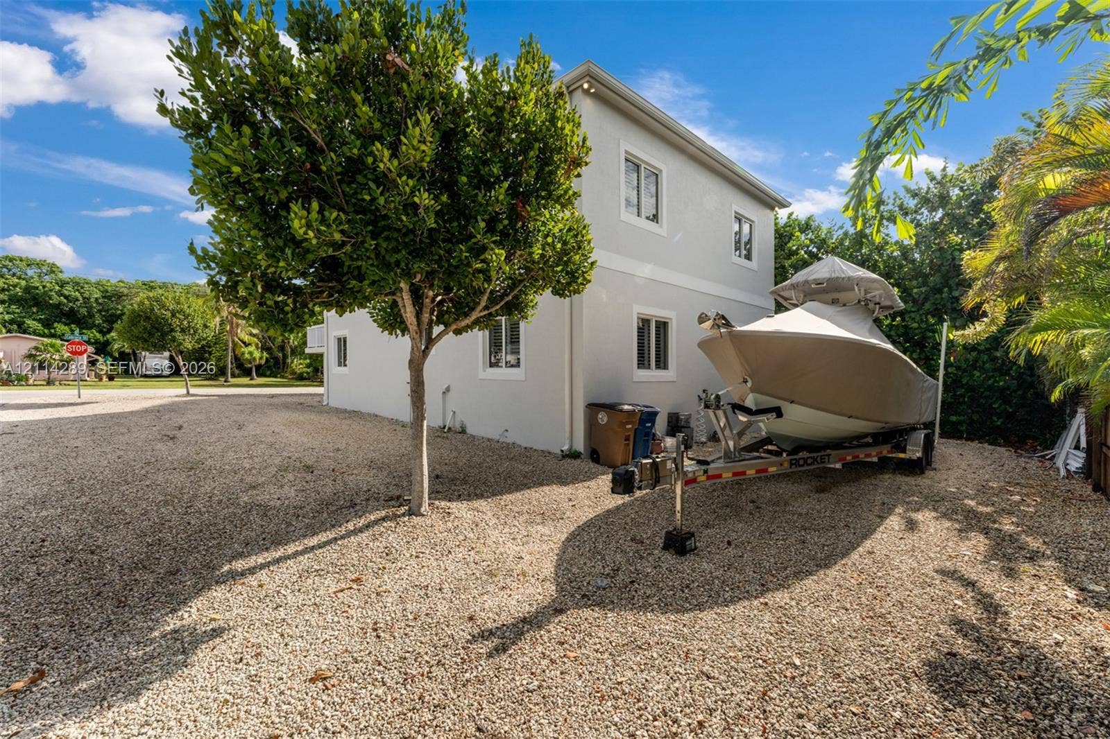 646 Cabrera Street, Key Largo, FL 33037 Two-story structure with a light-colored stucco exterior, multi-pane windows, and a gravel lot