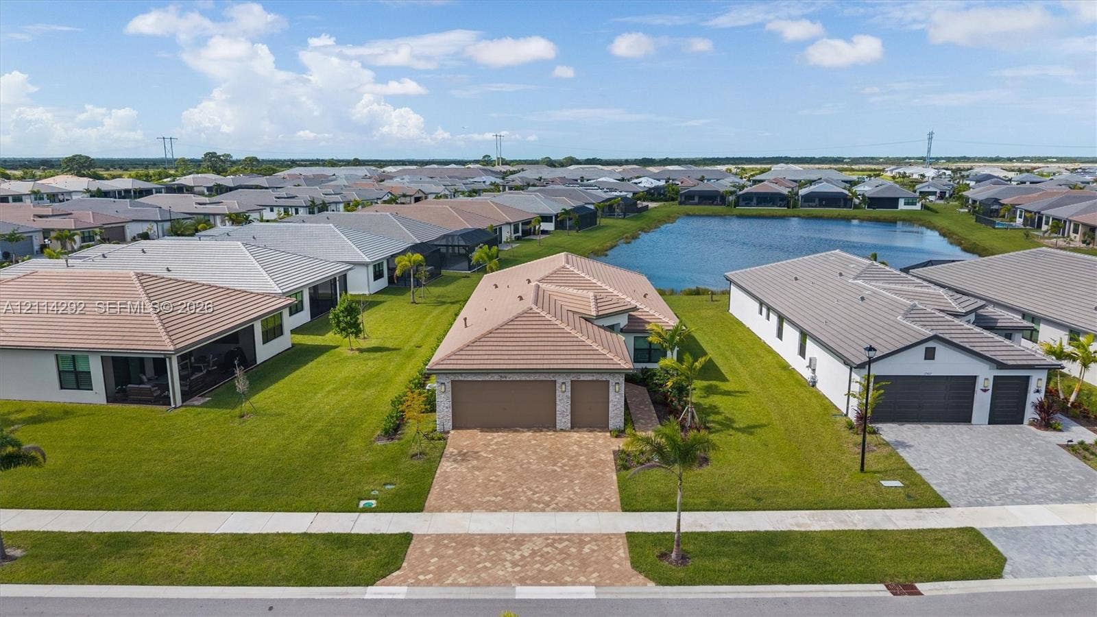 Single-story residence featuring a tile roof, multi-car garage, stone-accented facade, and paved driveway situated on a waterfront lot