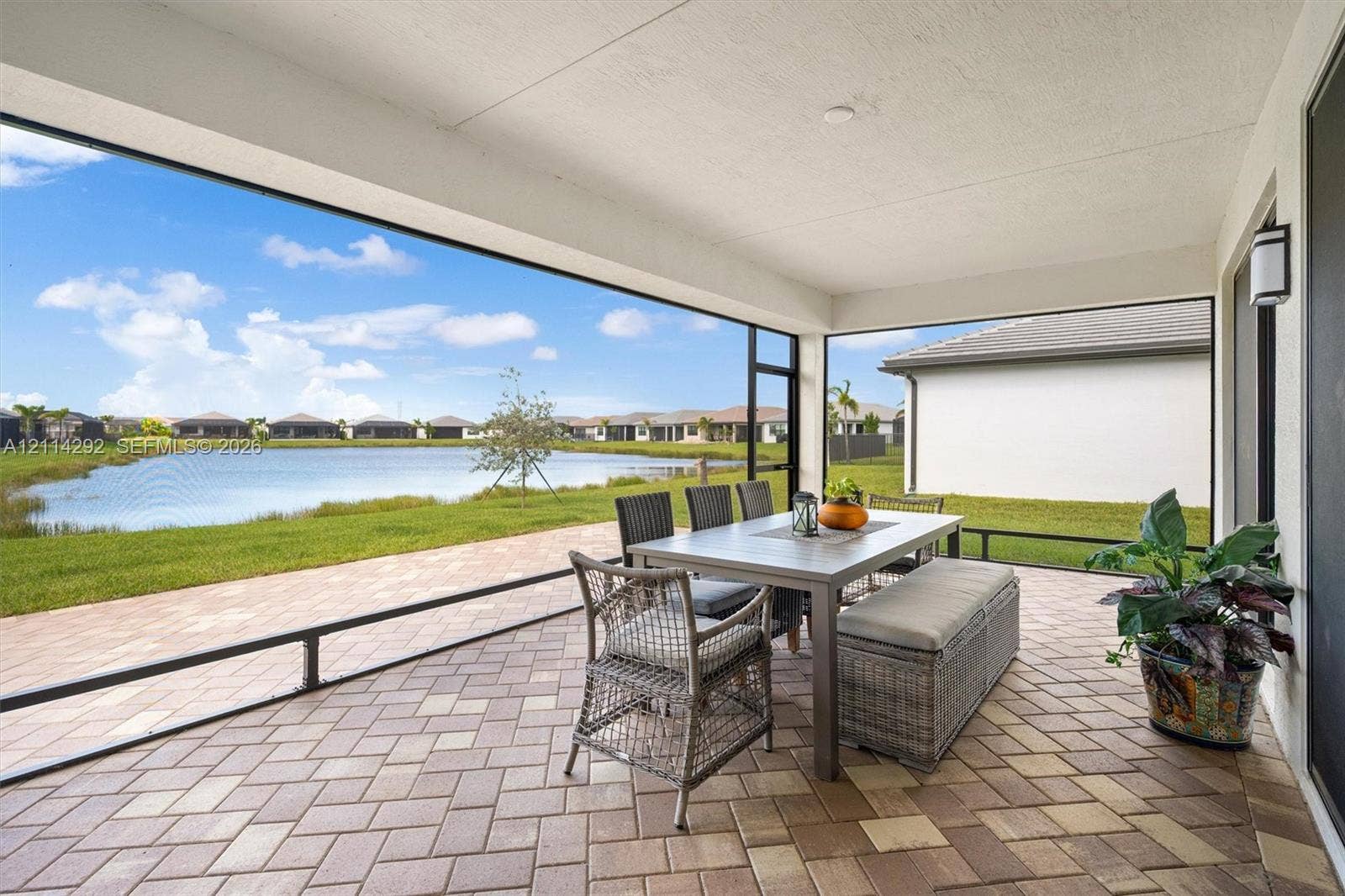 Covered screened-in patio featuring paver flooring and direct water frontage