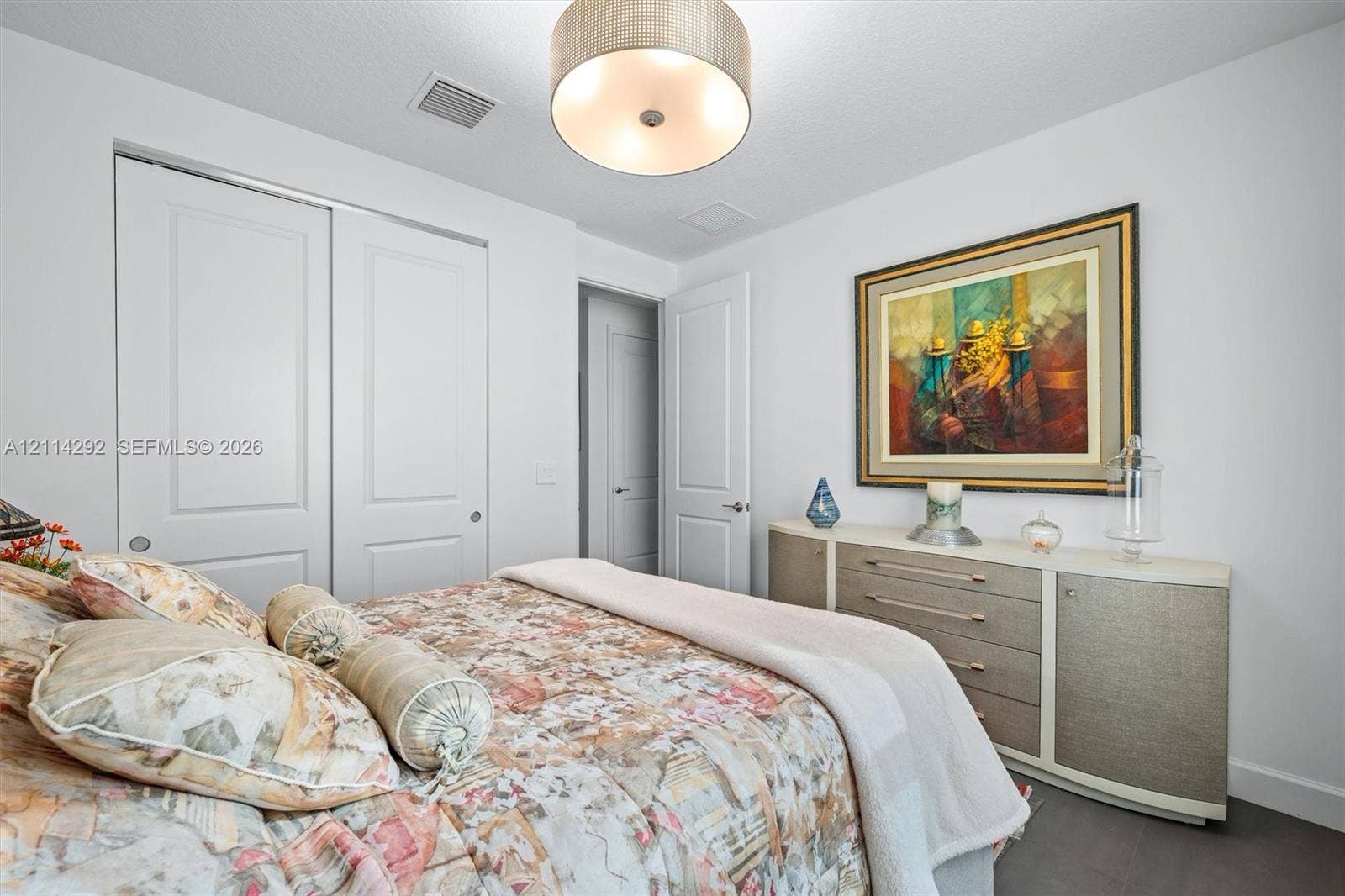 Room featuring dual-panel sliding closet doors, multi-panel interior door, and a drum-style ceiling light fixture