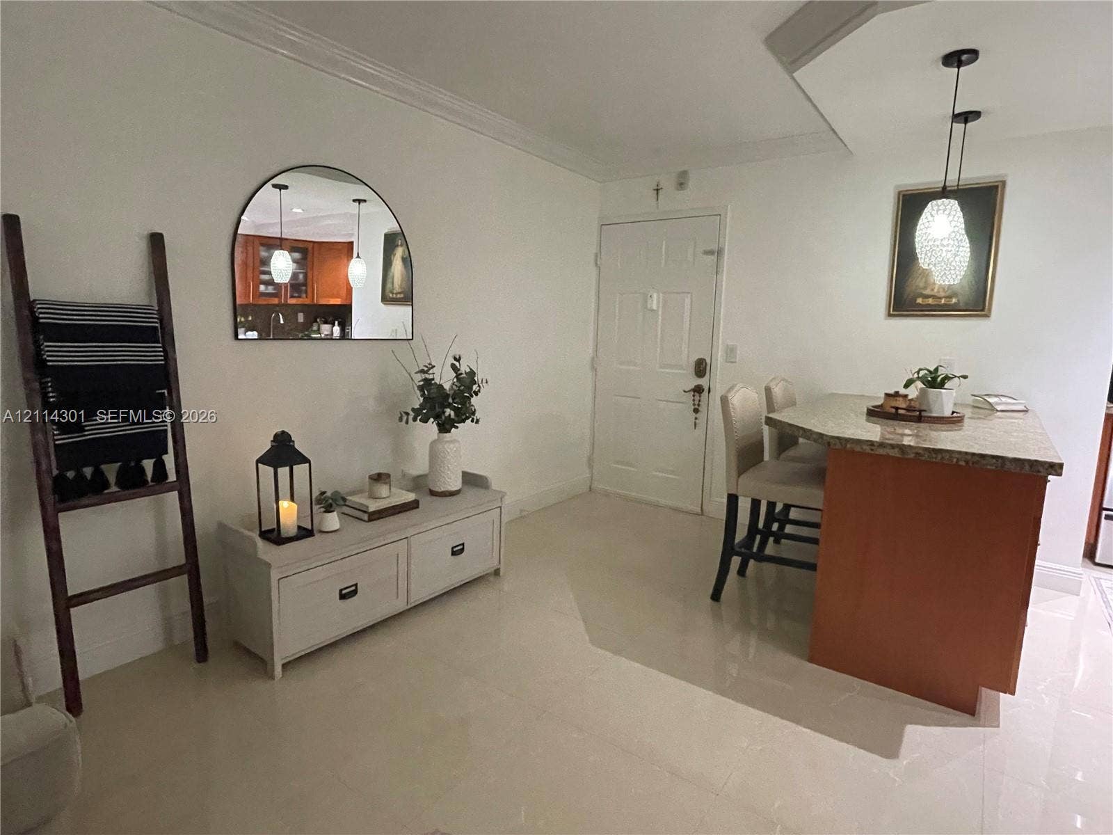 Kitchen featuring a stone-topped peninsula, dual pendant light fixtures, arched wall mirror, and polished tile flooring