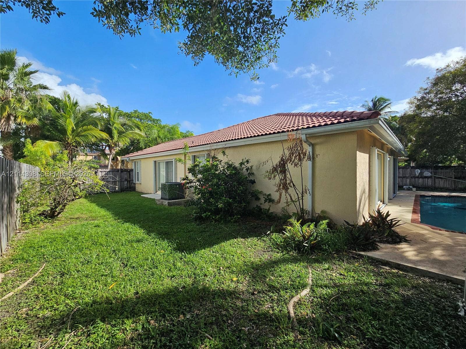 Backyard featuring a swimming pool, concrete pool deck, sliding glass doors, stucco exterior, and a tile roof