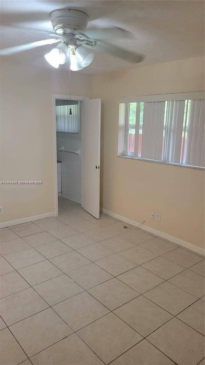 2131 N 19th Avenue, #2133, Hollywood, Hollywood, FL 33020 Neutral-toned room featuring large-format tile flooring, a multi-blade ceiling fan with integrated lighting, and a wide window with vertical blinds