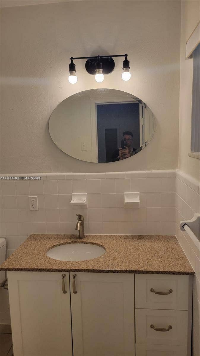 2131 N 19th Avenue, #2133, Hollywood, Hollywood, FL 33020 Vanity featuring a stone-composite countertop, undermount sink, white cabinetry with metallic hardware, oval mirror, and a three-light fixture