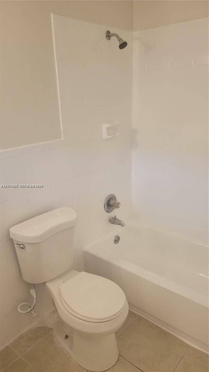 2131 N 19th Avenue, #2133, Hollywood, Hollywood, FL 33020 Full bathroom featuring a white porcelain toilet, a soaking tub with integrated shower head, tiled wall surround, and neutral-toned floor tile