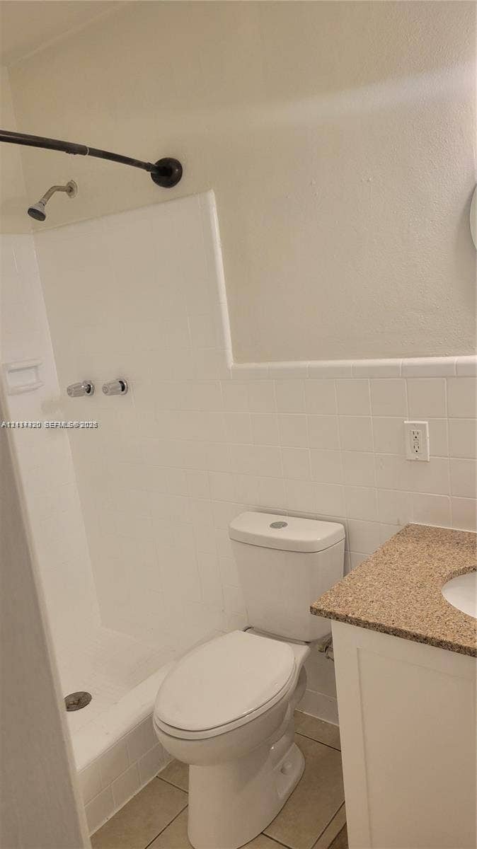 2131 N 19th Avenue, #2133, Hollywood, Hollywood, FL 33020 Bathroom featuring a shower with a surround, white ceramic wall tile, a vanity with a neutral-toned countertop, and tile flooring
