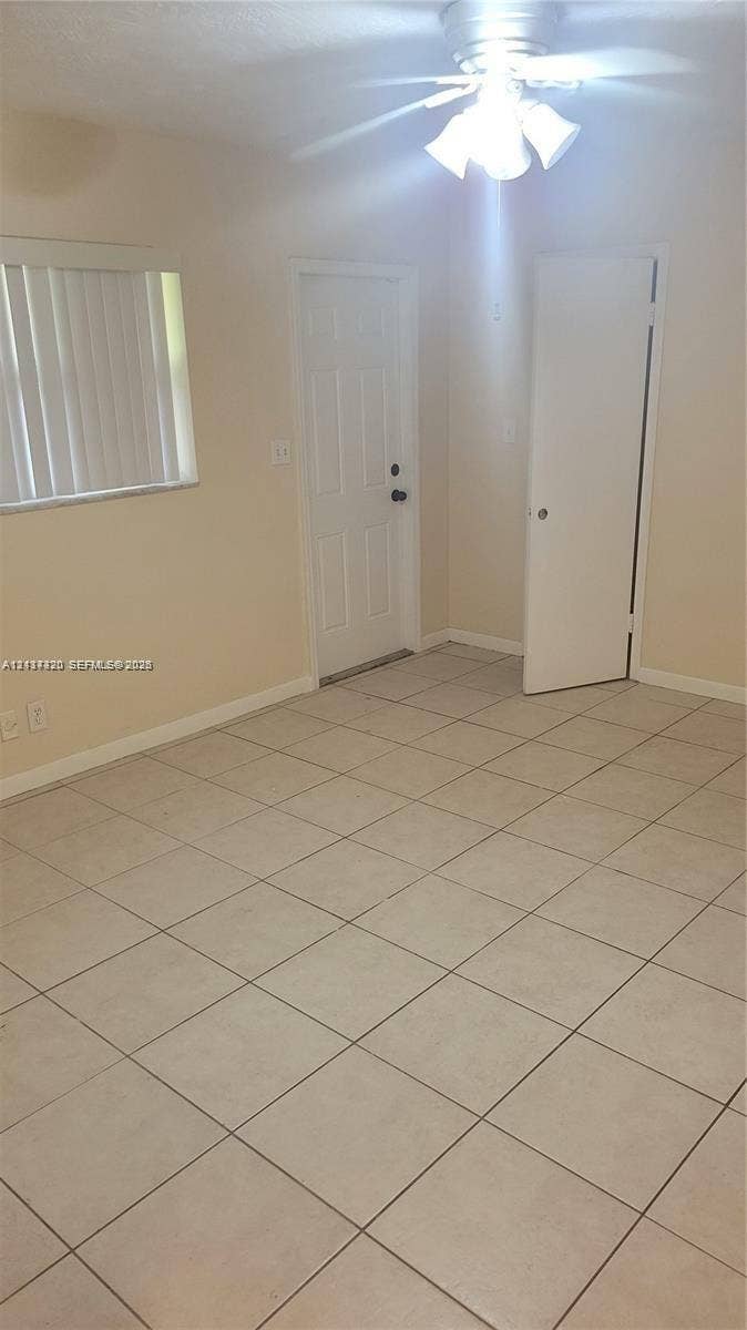 2131 N 19th Avenue, #2133, Hollywood, Hollywood, FL 33020 Neutral-toned interior space featuring large-format ceramic floor tiles, a ceiling-mounted light fixture with multi-directional shades, a six-panel exterior door, and a single-panel interior door