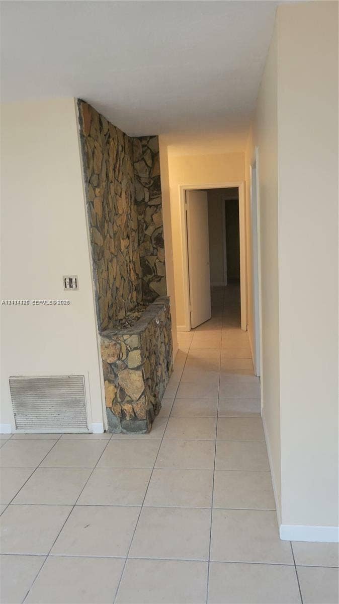2131 N 19th Avenue, #2133, Hollywood, Hollywood, FL 33020 Interior hallway featuring tile flooring and a built-in floor-to-ceiling stone accent wall