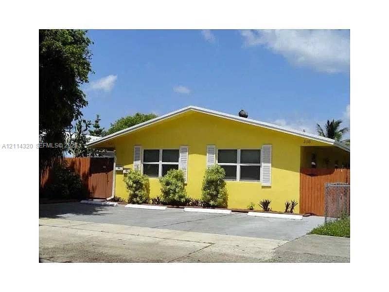 2131 N 19th Avenue, #2133, Hollywood, Hollywood, FL 33020 Single-story exterior featuring a vibrant stucco finish, multi-pane windows with louvered shutters, gabled roofline, and an asphalt parking area with concrete wheel stops
