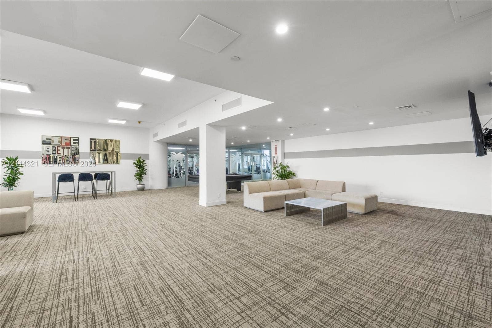 10350 W Bay Harbor Drive, #9C, Bay Harbor Islands, FL 33154 Open-concept recreation area featuring neutral patterned carpeting, recessed ceiling lighting, a structural support column, and floor-to-ceiling glass paneling