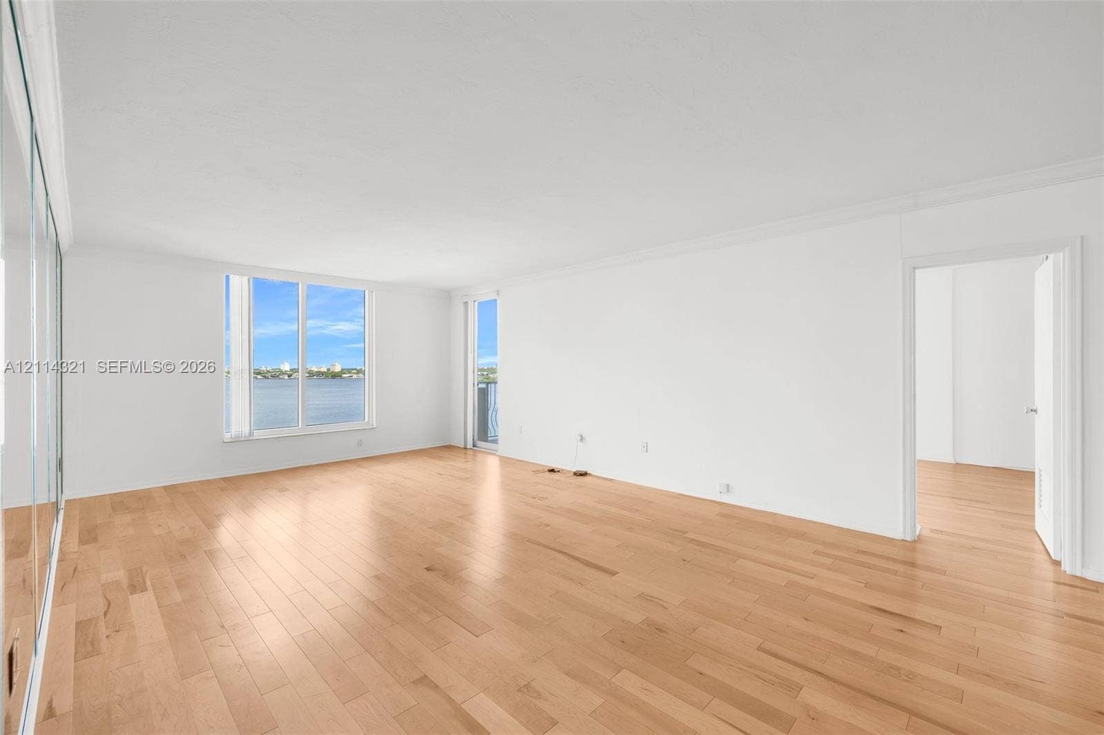 10350 W Bay Harbor Drive, #9C, Bay Harbor Islands, FL 33154 Open-concept room featuring wood-finish flooring, large windows, mirrored wall panels, and water scenery