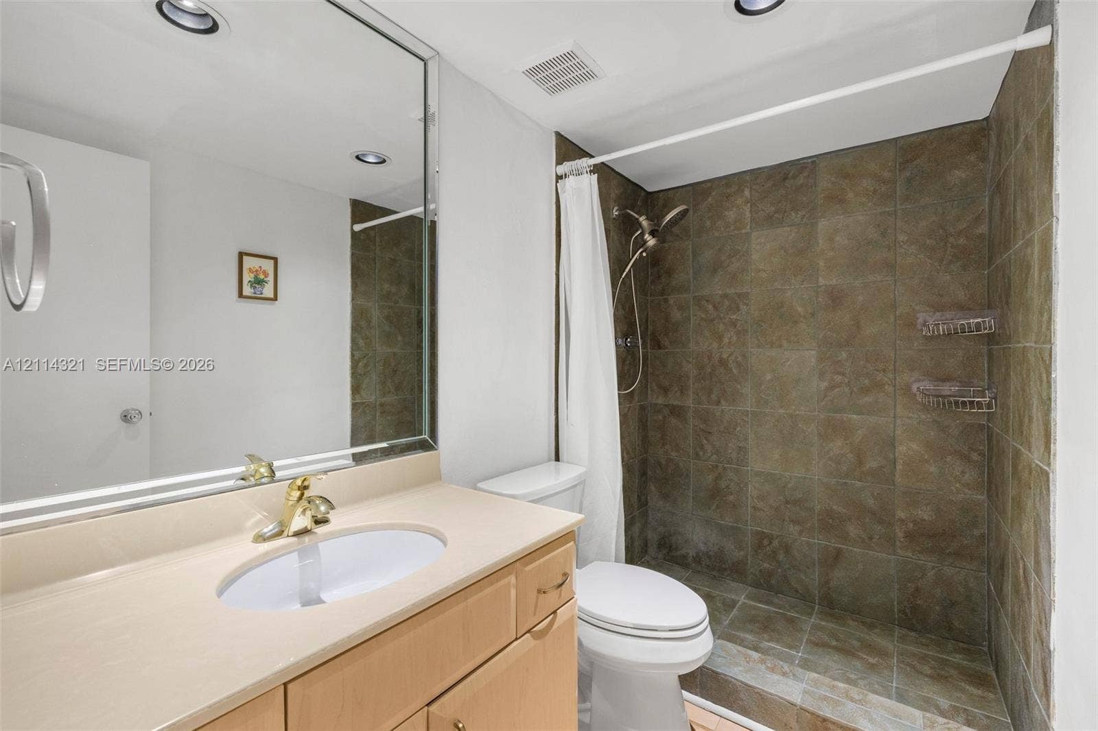 10350 W Bay Harbor Drive, #9C, Bay Harbor Islands, FL 33154 Bathroom featuring a vanity with a light-tone finish, solid surface countertop with an integrated oval basin, large wall-mounted mirror, recessed lighting, and a shower enclosure tiled with earth-toned stone