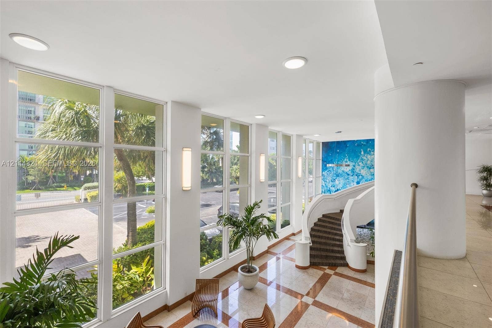 10350 W Bay Harbor Drive, #9C, Bay Harbor Islands, FL 33154 Floor-to-ceiling windows, sculptural curved staircase, stone flooring with decorative inlay, wall-mounted lighting fixtures, and high ceilings