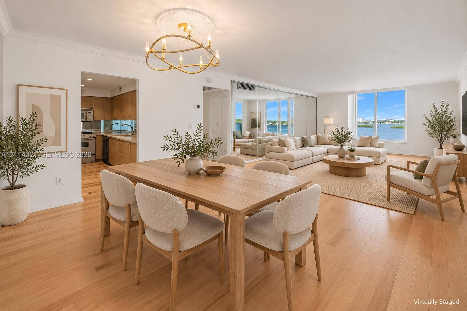 10350 W Bay Harbor Drive, #9C, Bay Harbor Islands, FL 33154 Open-concept living space featuring wood-finish flooring, a modern gold-tone circular chandelier, expansive windows, and a mirrored wall panel