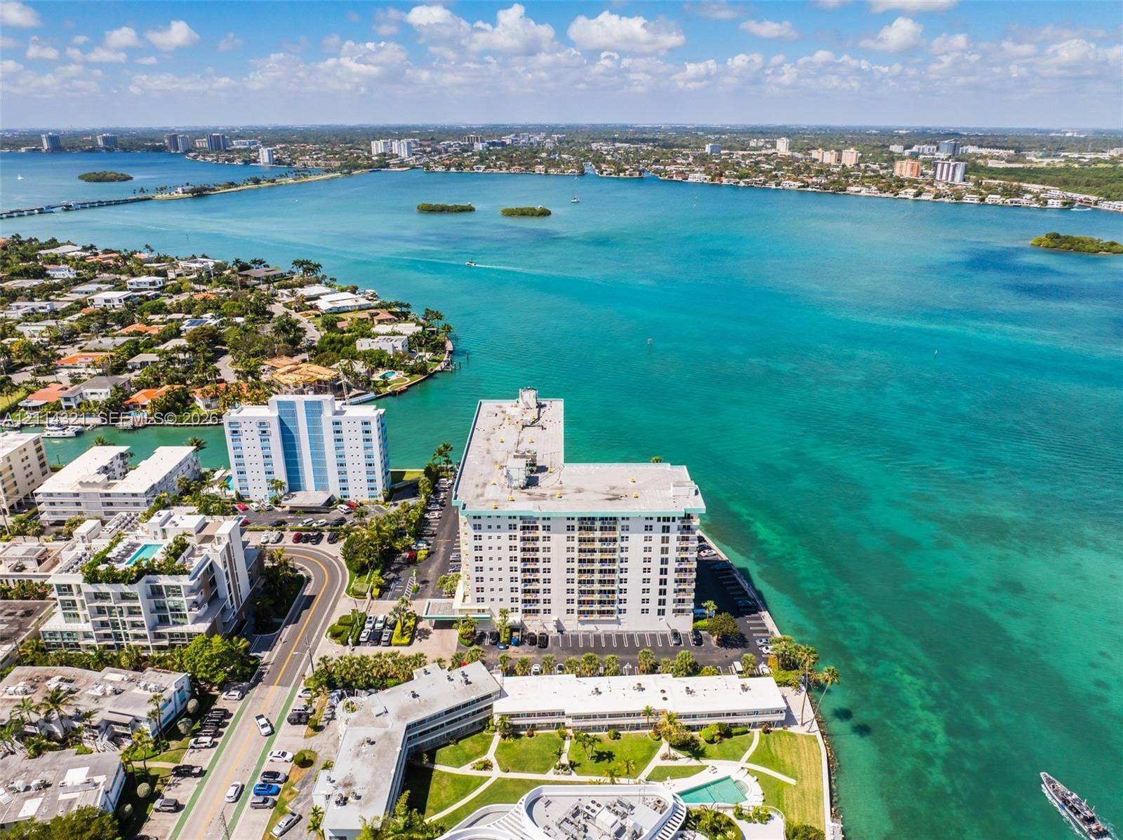 10350 W Bay Harbor Drive, #9C, Bay Harbor Islands, FL 33154 Aerial perspective of waterfront high-rise property featuring shoreline access, surface parking, and exterior balcony structures