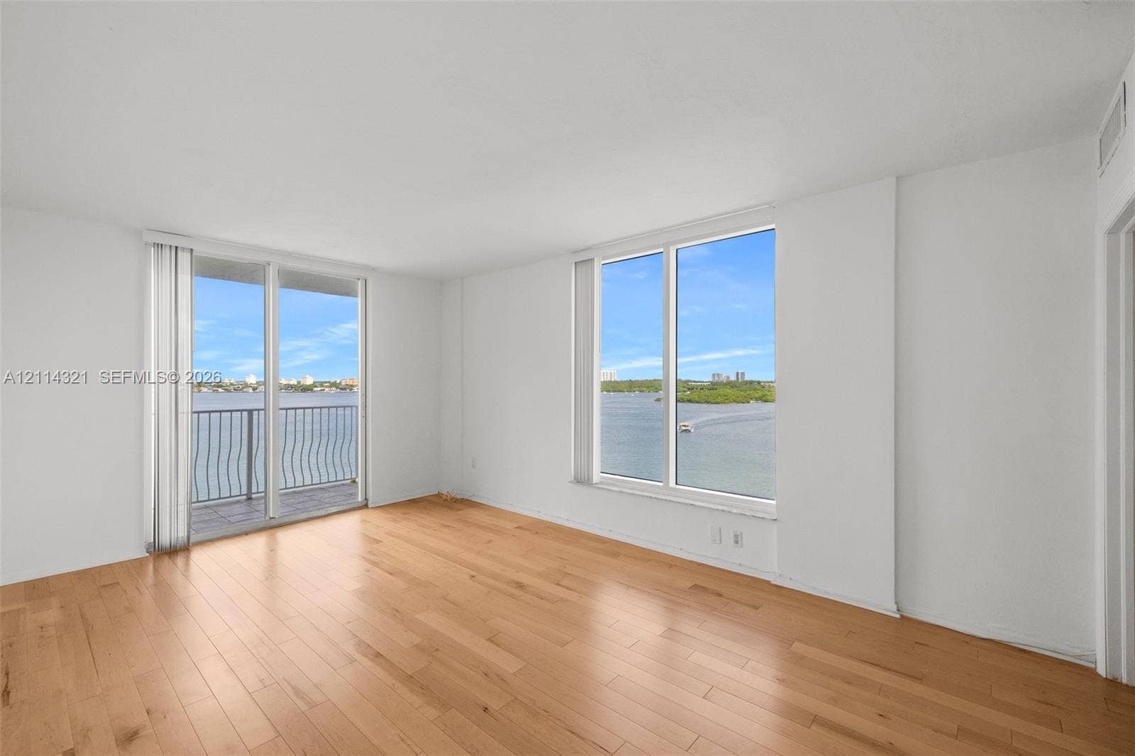 10350 W Bay Harbor Drive, #9C, Bay Harbor Islands, FL 33154 Living area featuring wood-finish flooring, floor-to-ceiling windows, and access to a balcony overlooking a water body