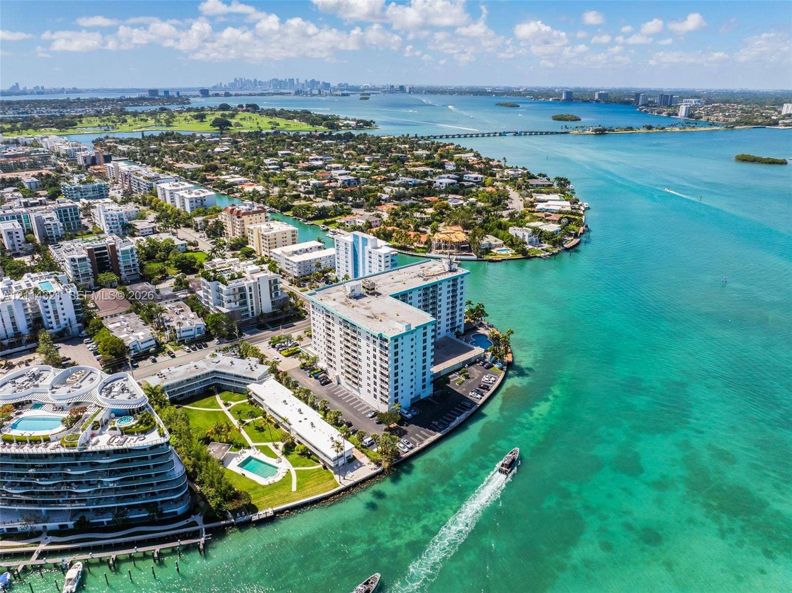 10350 W Bay Harbor Drive, #9C, Bay Harbor Islands, FL 33154 Aerial perspective of a high-rise waterfront condominium complex featuring direct shoreline access and surrounding tropical landscape