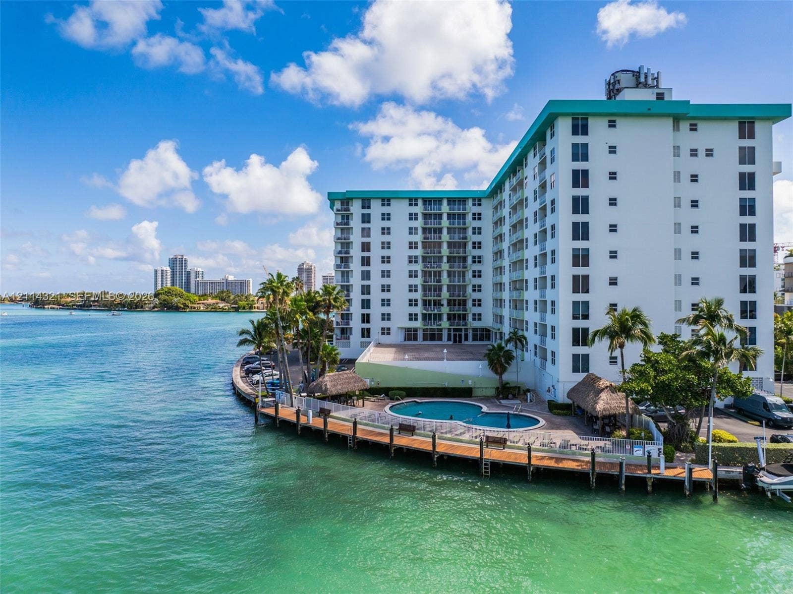 10350 W Bay Harbor Drive, #9C, Bay Harbor Islands, FL 33154 Waterfront multi-story building featuring an outdoor swimming pool, a perimeter wooden deck, and thatched-roof structures