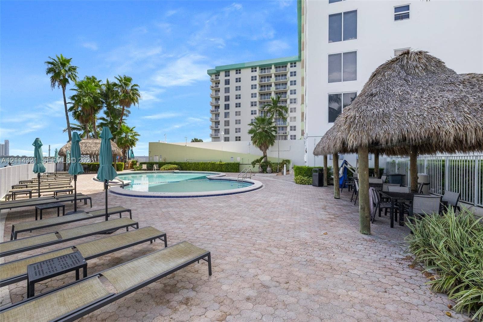 10350 W Bay Harbor Drive, #9C, Bay Harbor Islands, FL 33154 Swimming pool with a paved deck, thatched-roof cabana, and tropical landscaping