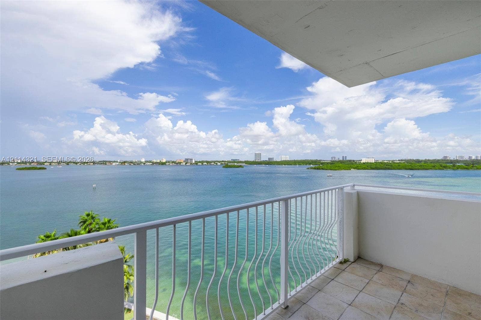 10350 W Bay Harbor Drive, #9C, Bay Harbor Islands, FL 33154 Private balcony featuring stone tile flooring and white metal railing overlooking an expansive bay and coastal horizon