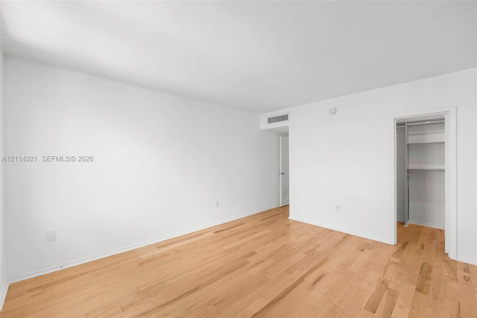 10350 W Bay Harbor Drive, #9C, Bay Harbor Islands, FL 33154 Neutral-toned interior featuring wood-finish flooring, white walls, and a walk-in closet with built-in shelving