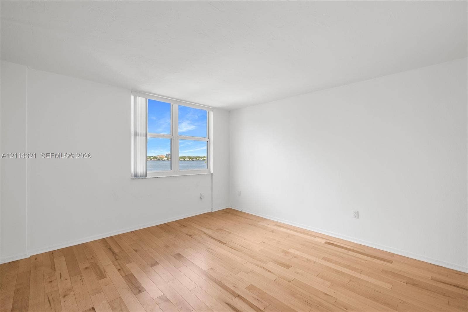 10350 W Bay Harbor Drive, #9C, Bay Harbor Islands, FL 33154 Interior room featuring light-toned wood-finish flooring, white walls, and a large window with white vertical blinds