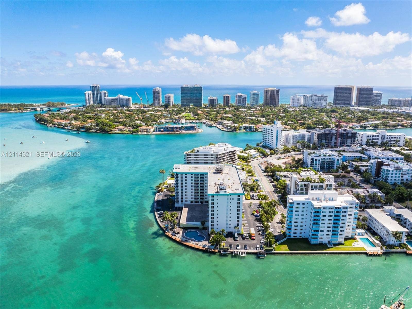 10350 W Bay Harbor Drive, #9C, Bay Harbor Islands, FL 33154 Aerial perspective featuring a waterfront high-rise building with a private swimming pool, situated on a coastal peninsula with direct water access