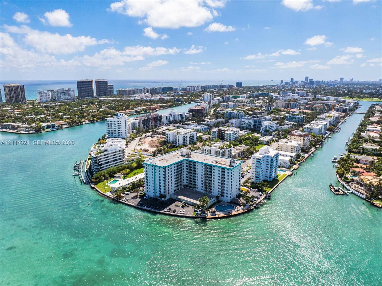 10350 W Bay Harbor Drive, #9C, Bay Harbor Islands, FL 33154 Waterfront high-rise building situated on a peninsula, featuring exterior surface parking, a ground-level pool, and direct access to surrounding waterways