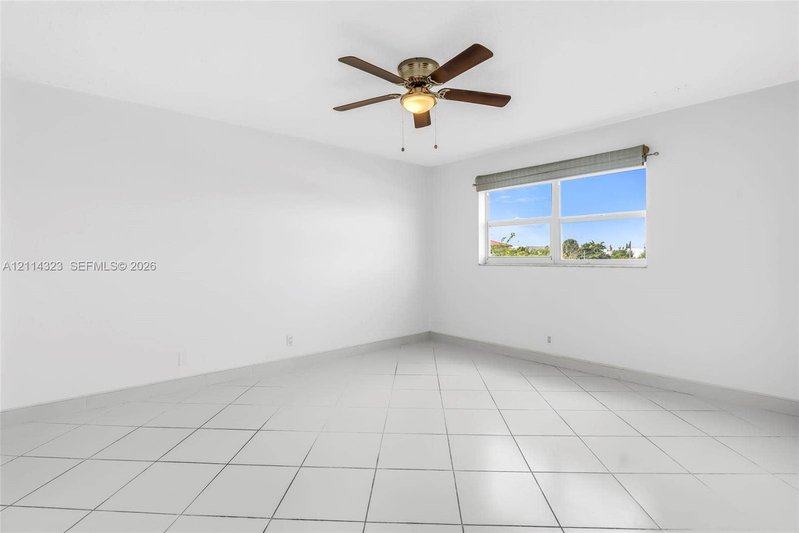 Neutral interior featuring white tile flooring, white walls, and a ceiling-mounted fan with integrated light fixture