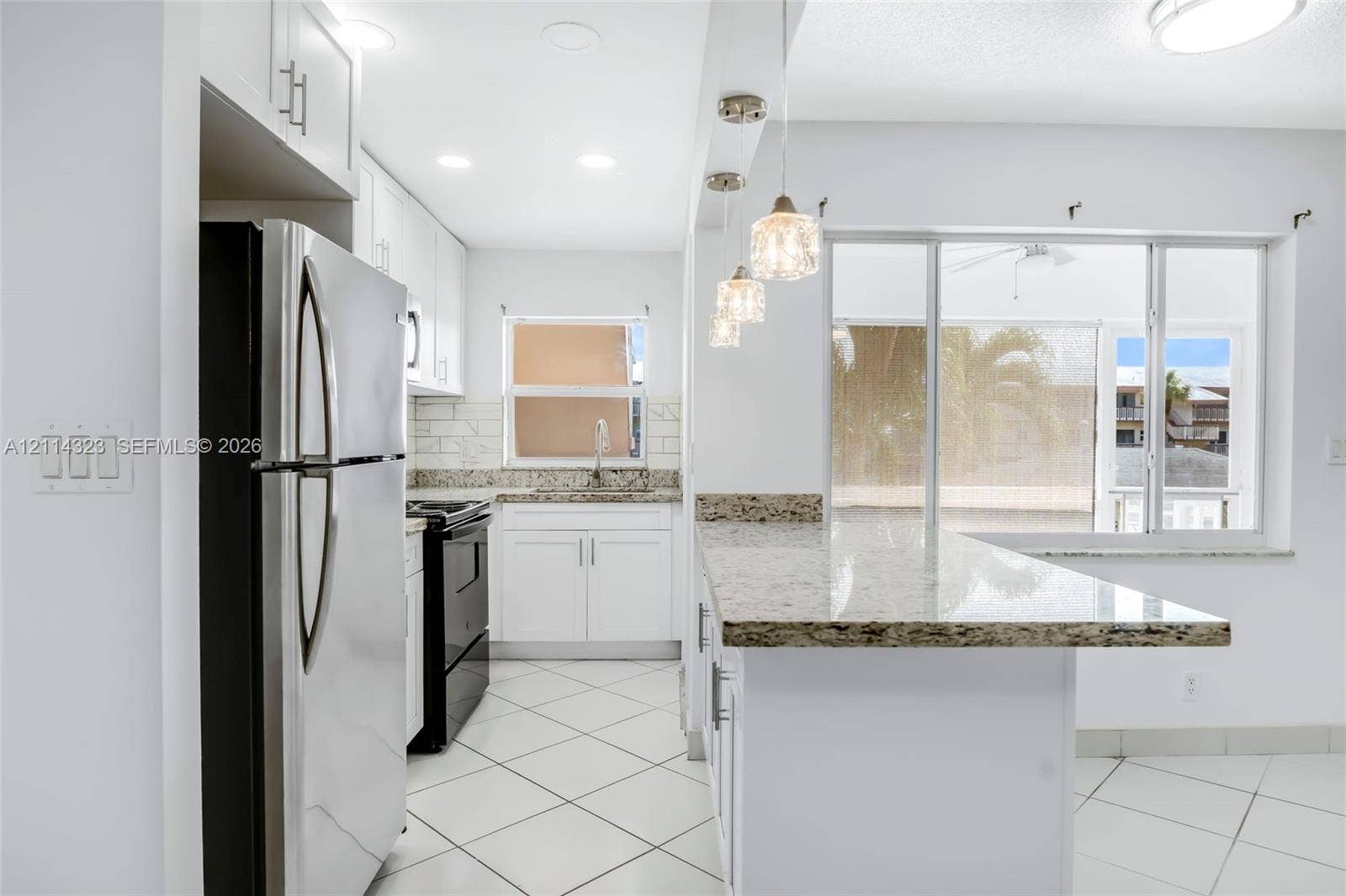 Kitchen featuring white shaker-style cabinetry, stone-finish countertops, tile flooring, subway tile backsplash, and decorative pendant lighting