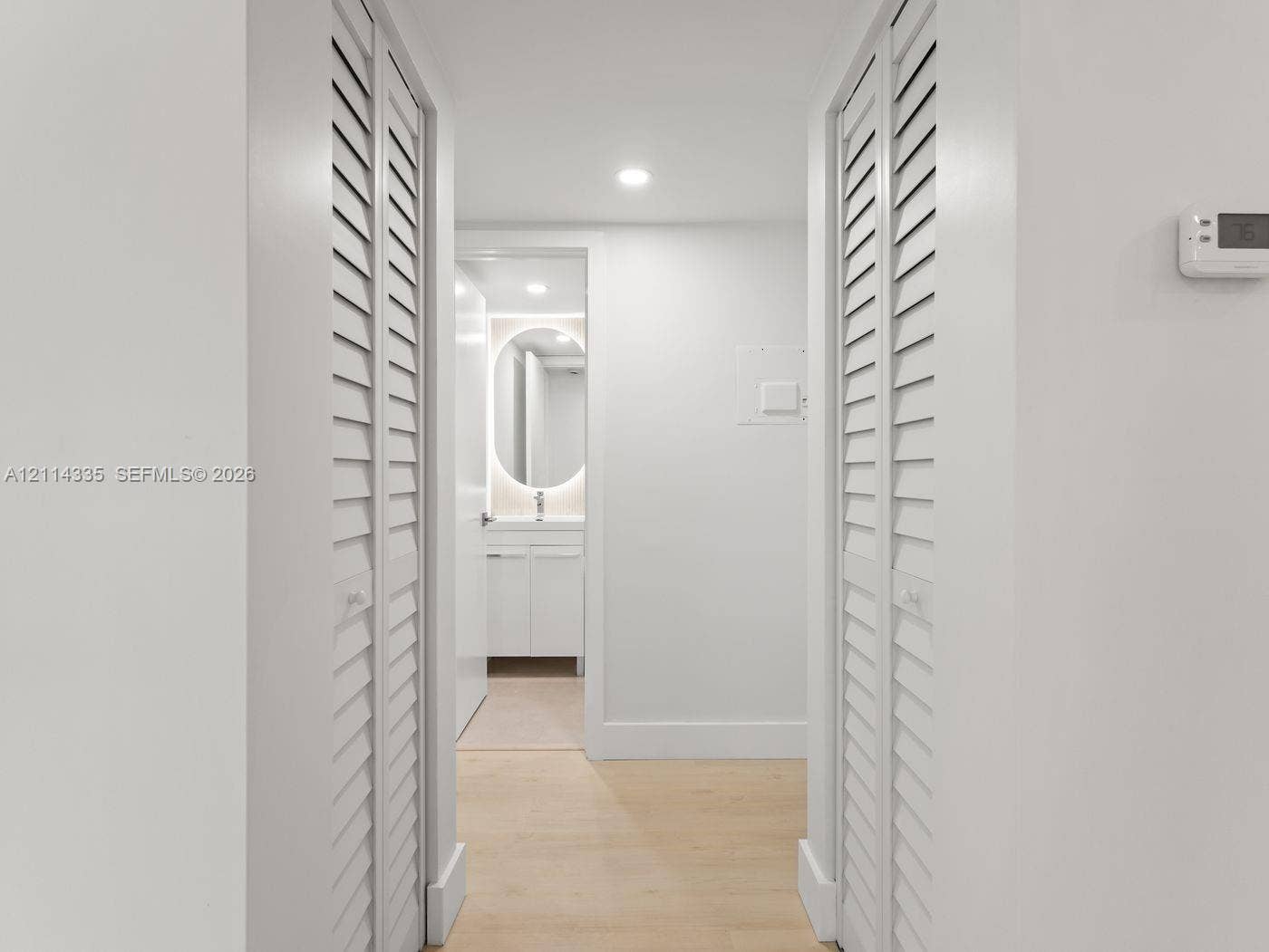 2930 Day Avenue, #N102, Miami, Miami, FL 33133 Interior hallway featuring dual white louvered closet doors, recessed ceiling lighting, and wood-finish flooring