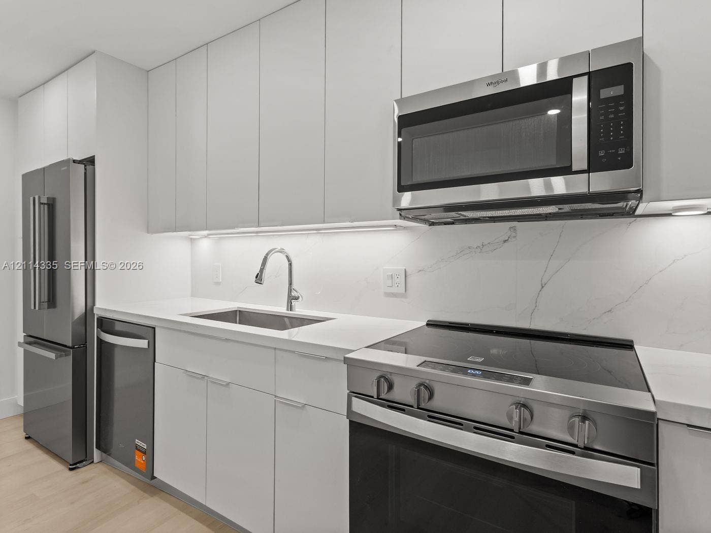 2930 Day Avenue, #N102, Miami, Miami, FL 33133 Kitchen featuring flat-panel white cabinetry, stone-patterned backsplash, stainless steel appliances, and integrated under-cabinet lighting