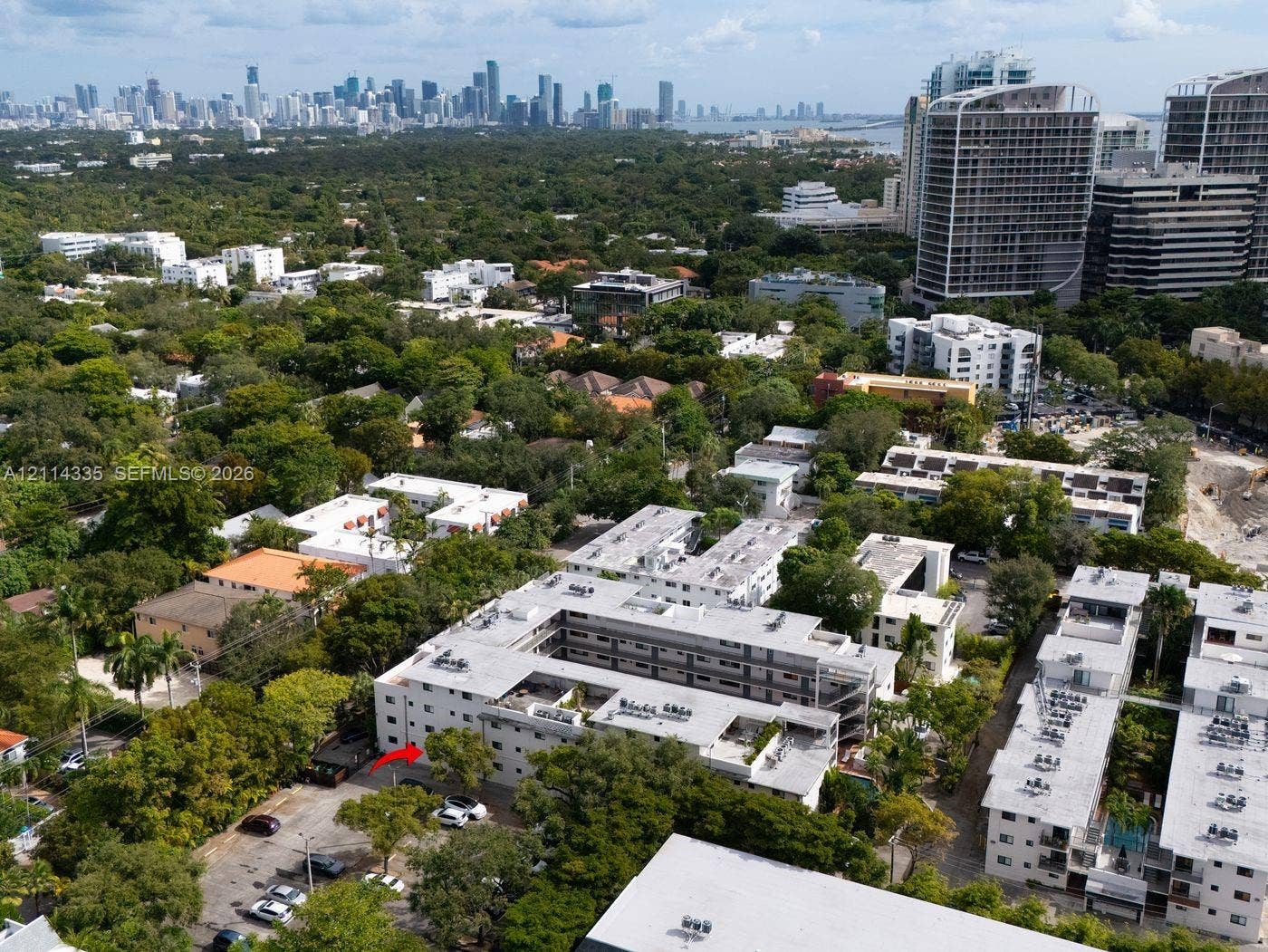 2930 Day Avenue, #N102, Miami, Miami, FL 33133 Aerial perspective of mid-rise multi-unit residential building featuring a courtyard layout, flat roof construction, exterior surface parking, and dense mature landscaping