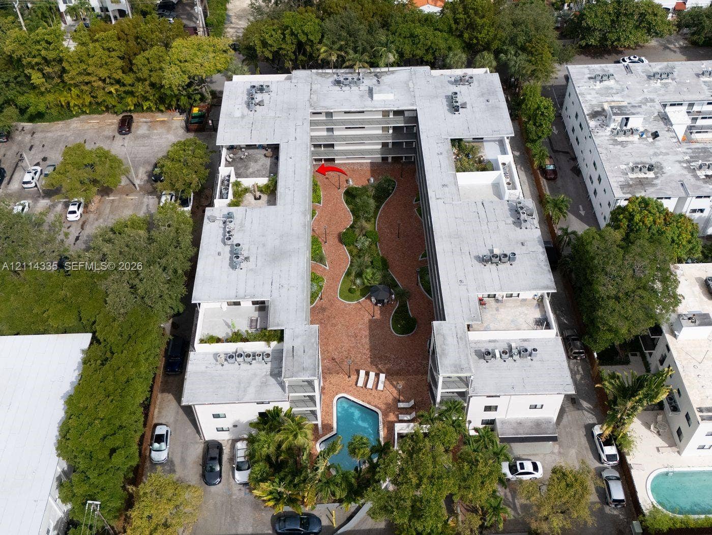2930 Day Avenue, #N102, Miami, Miami, FL 33133 Multi-story residential complex featuring a central courtyard with paved walkways, manicured landscaping, and an outdoor swimming pool