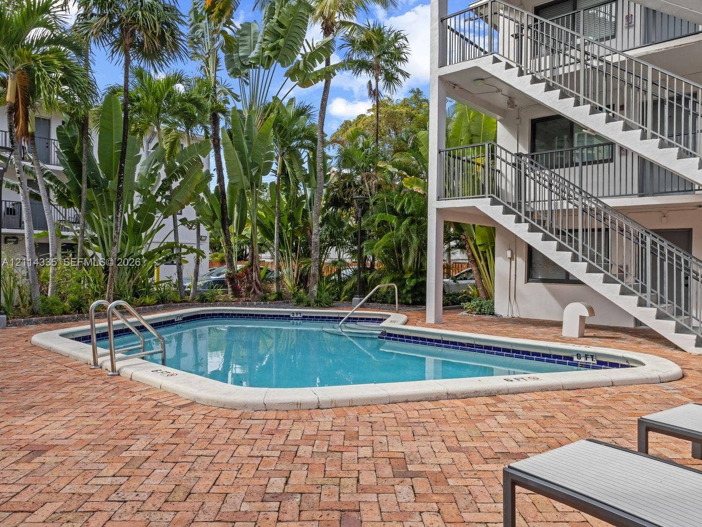2930 Day Avenue, #N102, Miami, Miami, FL 33133 In-ground swimming pool with a tiled perimeter, expansive brick-paver deck, and surrounding mature palm trees