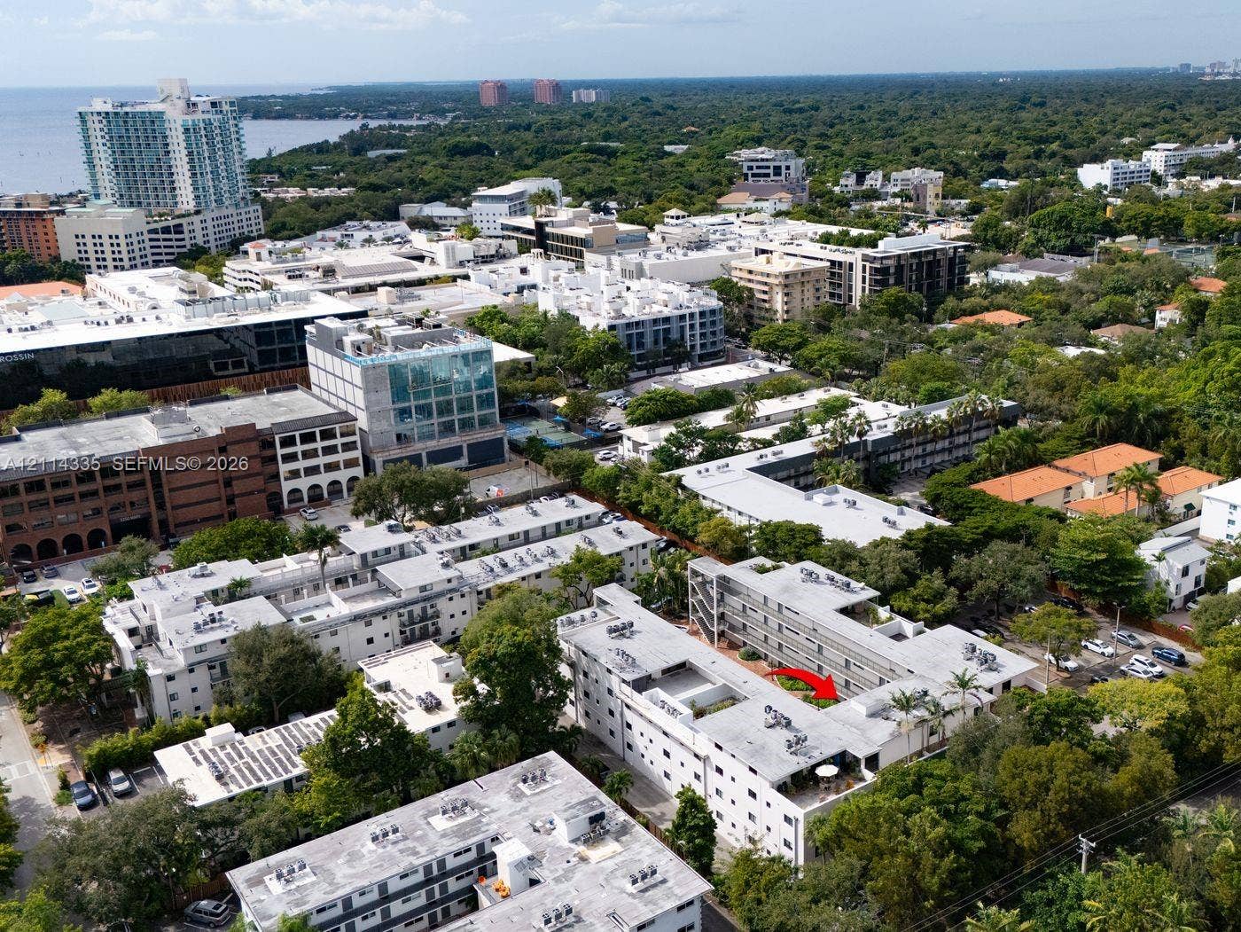 2930 Day Avenue, #N102, Miami, Miami, FL 33133 Aerial perspective featuring a multi-story building within a dense urban landscape, exterior paved parking areas, and mature tree canopy