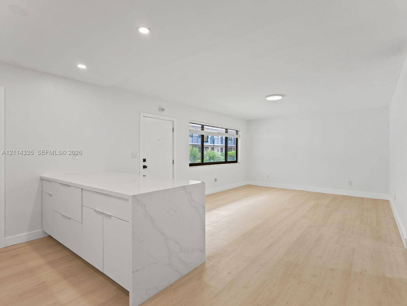 2930 Day Avenue, #N102, Miami, Miami, FL 33133 Open-concept interior featuring light wood-finish flooring, white cabinetry with a waterfall edge stone countertop, and recessed lighting