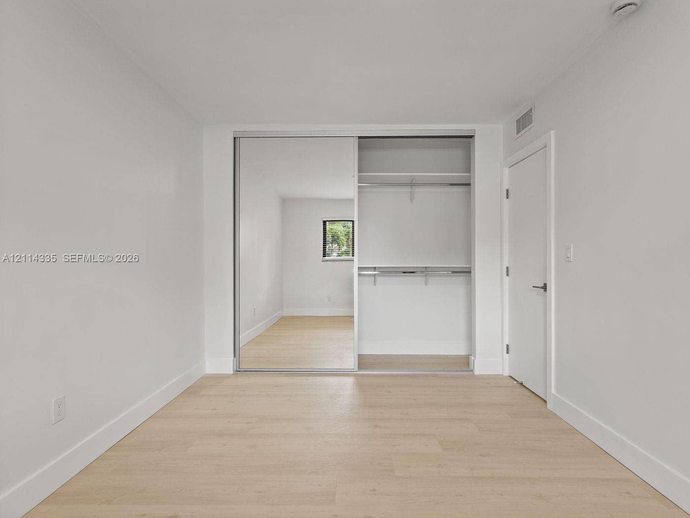 2930 Day Avenue, #N102, Miami, Miami, FL 33133 Room featuring wood-finish flooring, sliding mirror closet doors, and built-in closet shelving