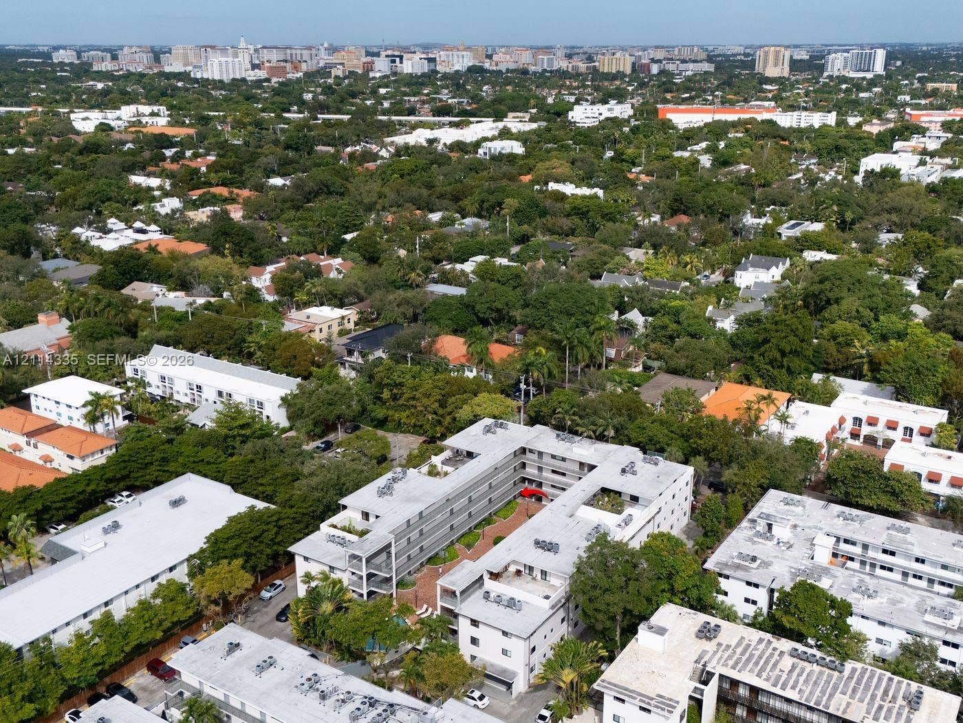 2930 Day Avenue, #N102, Miami, Miami, FL 33133 Aerial perspective of a multi-story residential complex featuring a central courtyard with paved hardscaping, perimeter landscaping, and rooftop mechanical systems