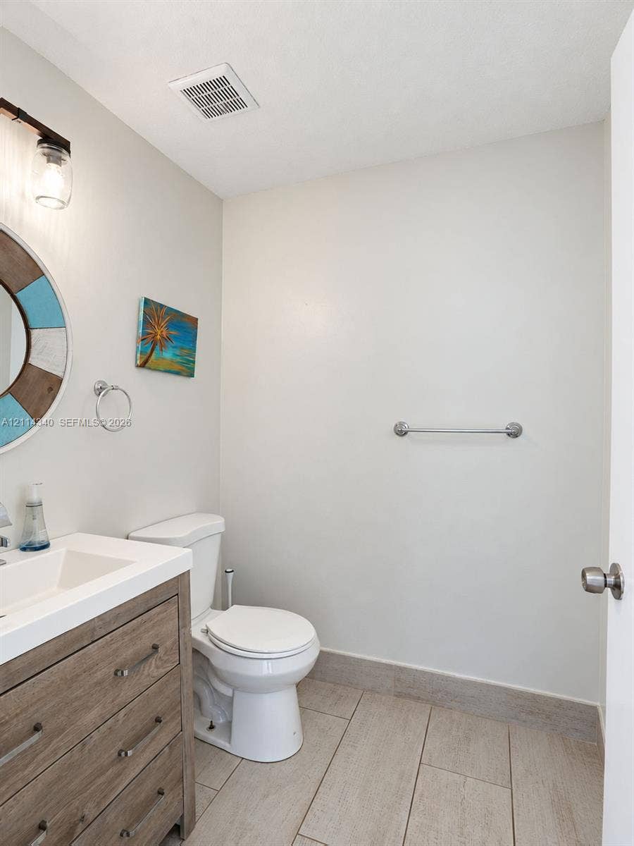 3586 SW 50th Street, Hollywood, FL 33312 Bathroom featuring a wood-finish vanity with an integrated rectangular sink, large-format tile flooring, a wall-mounted metal towel bar, and a multi-light fixture