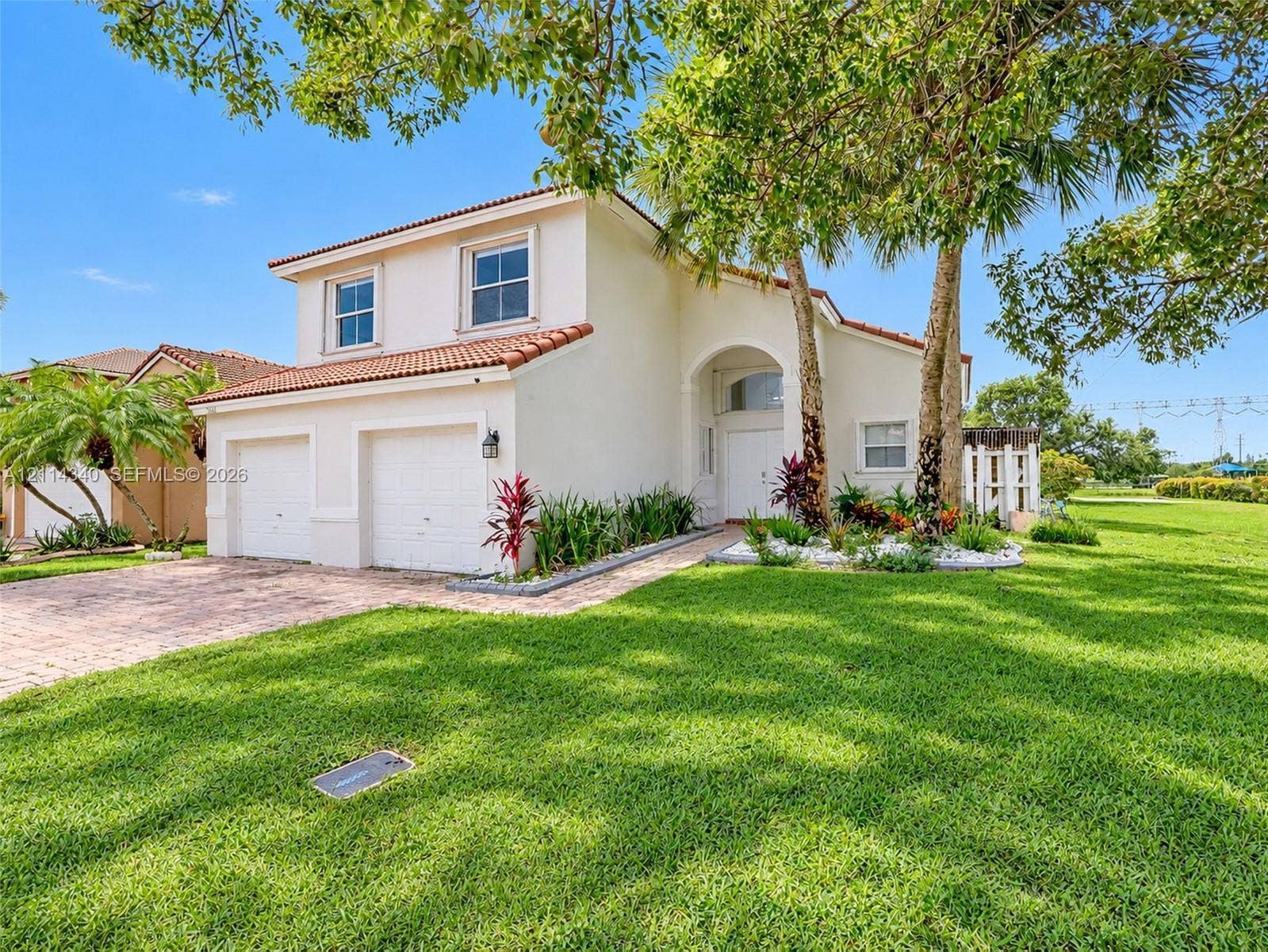 3586 SW 50th Street, Hollywood, FL 33312 Stucco exterior residence featuring a terracotta-tile roof, two-car garage, arched entryway, and paver driveway