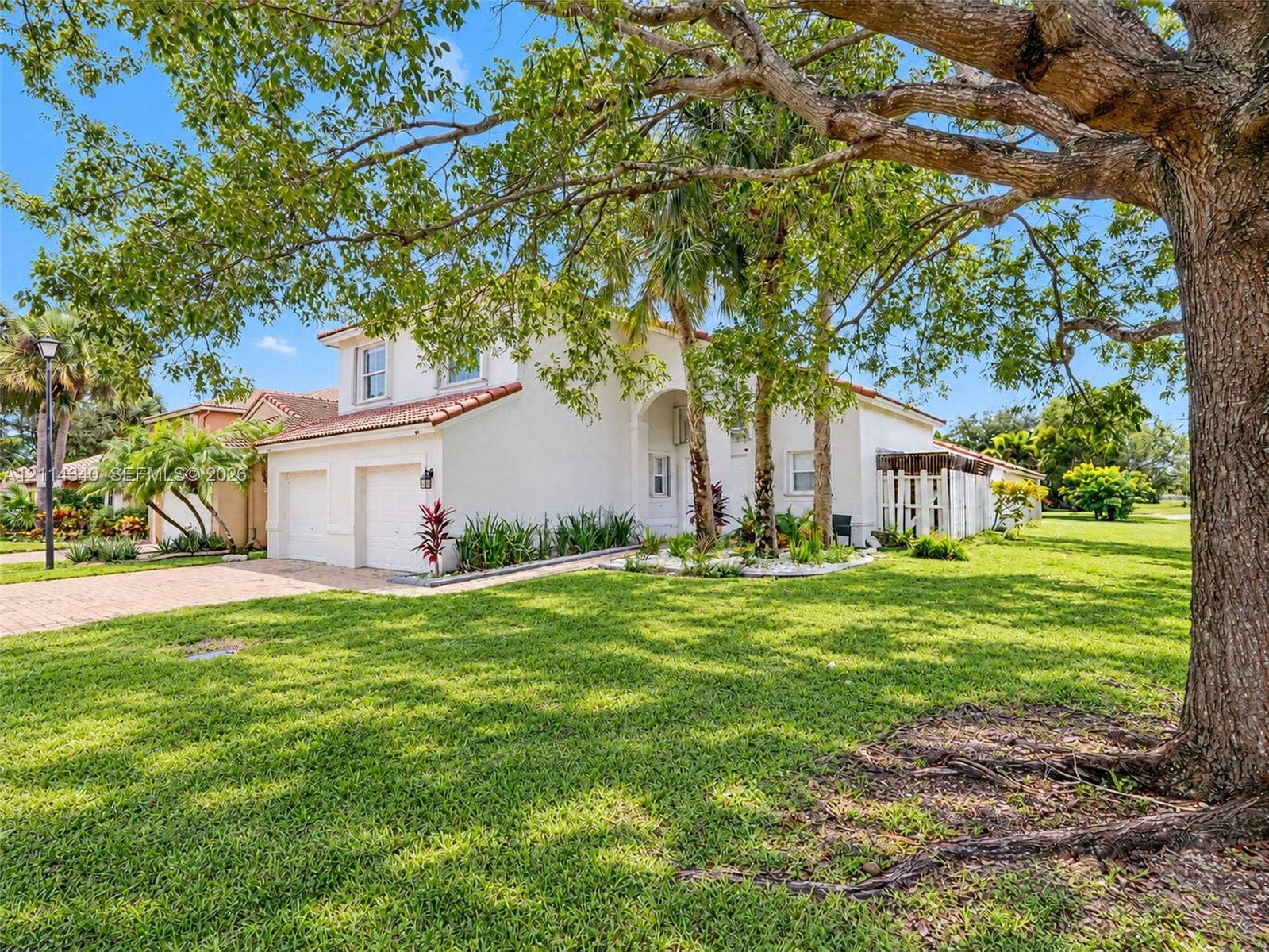 3586 SW 50th Street, Hollywood, FL 33312 Stucco exterior featuring a red tile roof, two-car garage, paver driveway, and mature landscaping