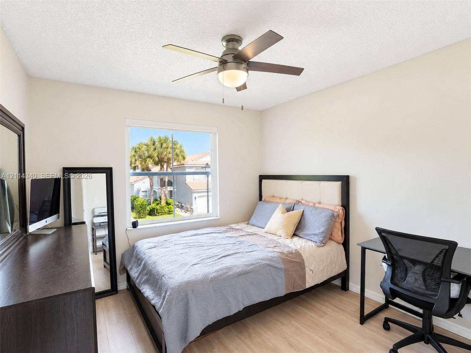 3586 SW 50th Street, Hollywood, FL 33312 Light-filled room featuring wood-finish flooring, a central ceiling fan with integrated lighting, and a single-pane window with exterior palm tree scenery